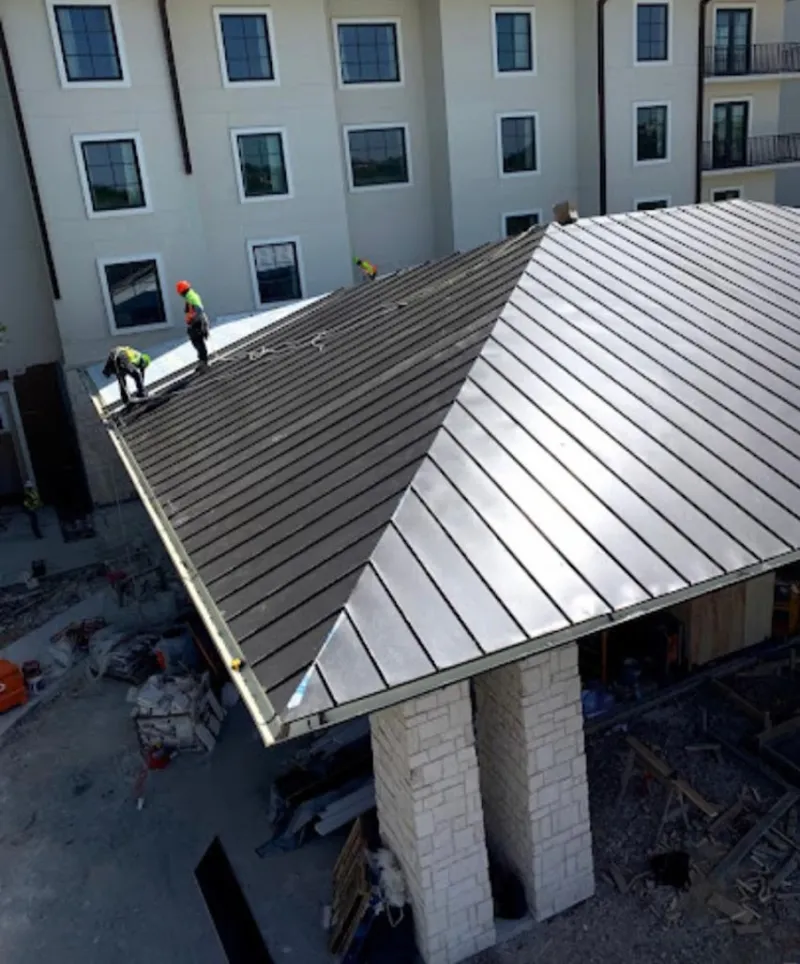 Crew installing standing seam metal roof panels on a commercial project in Vernal